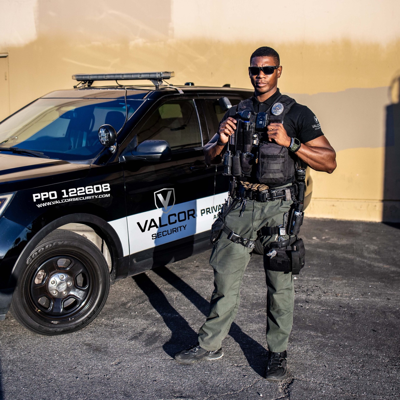 Officer beside a marked Valcor Security patrol vehicle
