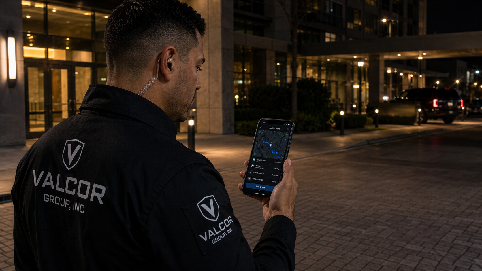 Valcor Security officer reviewing a shift-tracking app on patrol at night